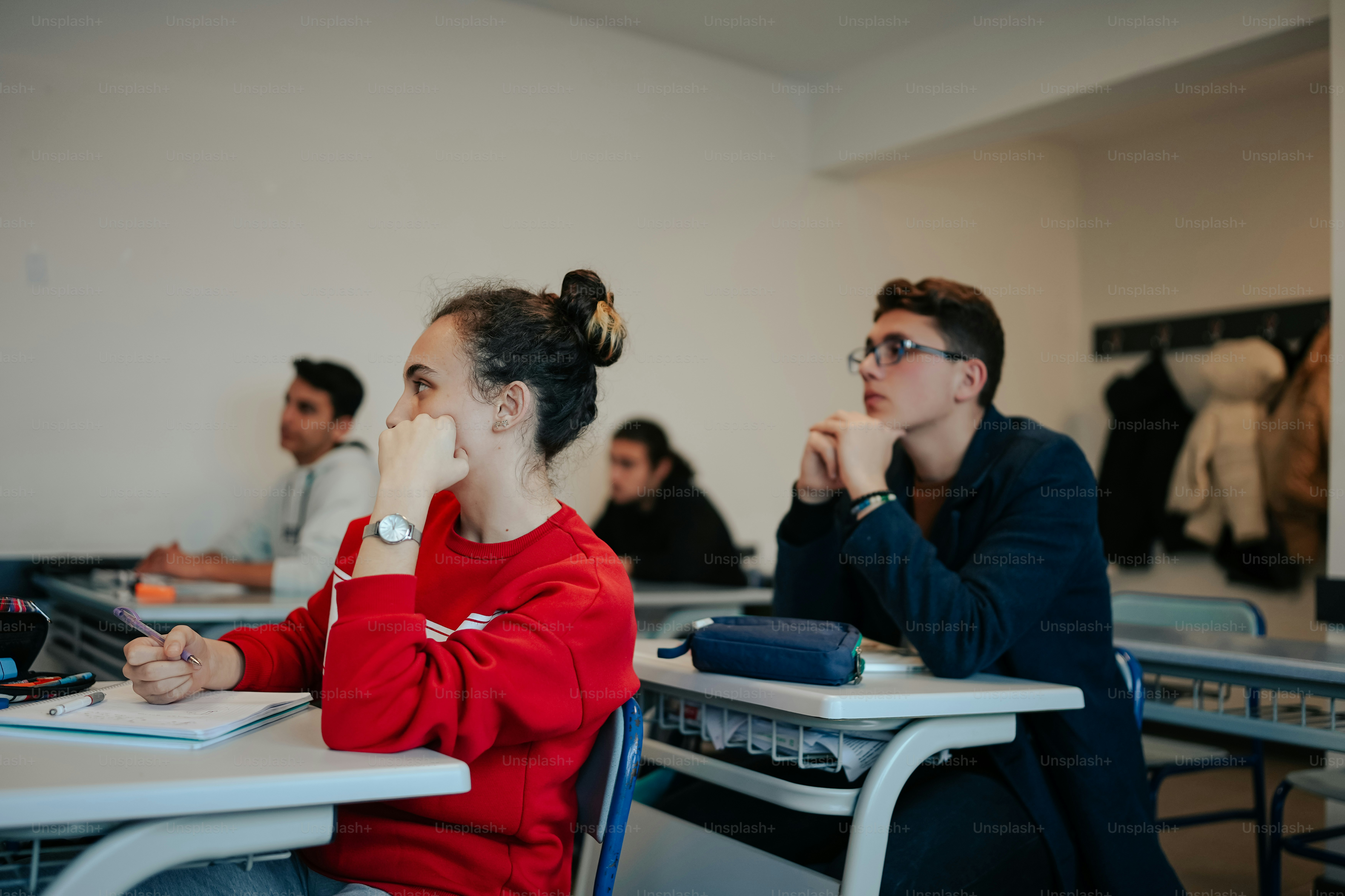 Un grupo de personas sentadas en escritorios en un aula
