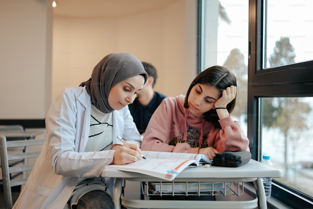 two people sitting at a table with a book