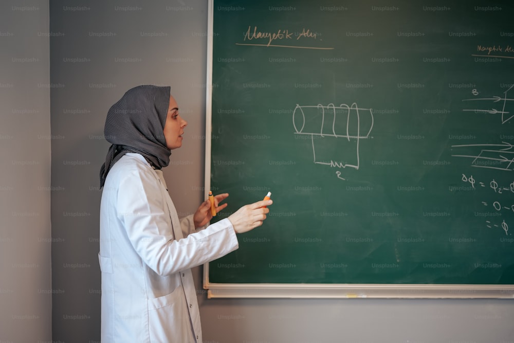 Una mujer con un hijab escribiendo en una pizarra