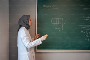 uma mulher em um hijab escrevendo em um quadro negro