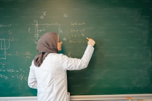 a woman writing on a blackboard with a marker