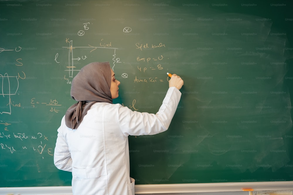 a woman writing on a blackboard with a marker