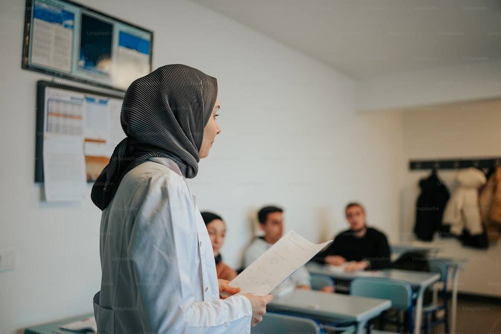 uma mulher em um hijab em pé em uma sala de aula