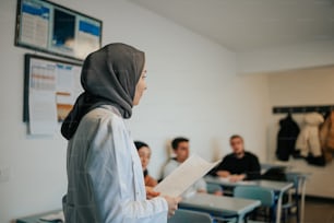 uma mulher em um hijab em pé em uma sala de aula