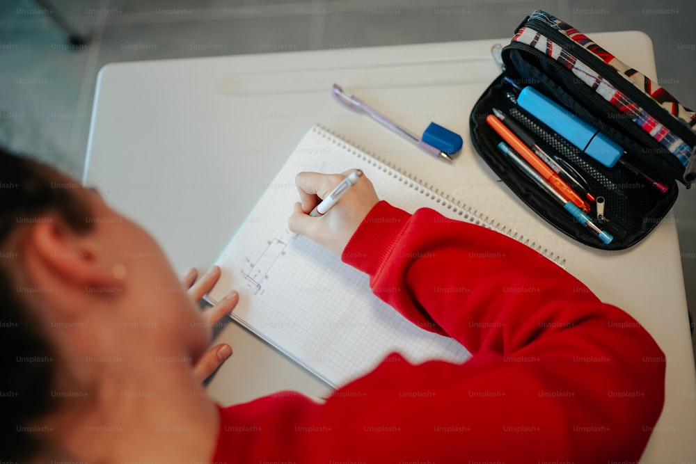 a person writing on a notebook with a pencil