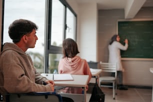 a man and a woman sitting at desks in front of a blackboard