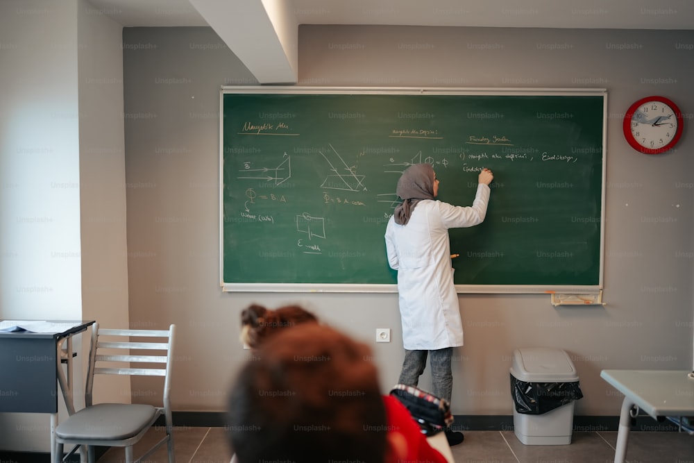 Eine Person, die in einem Klassenzimmer auf eine Kreidetafel schreibt