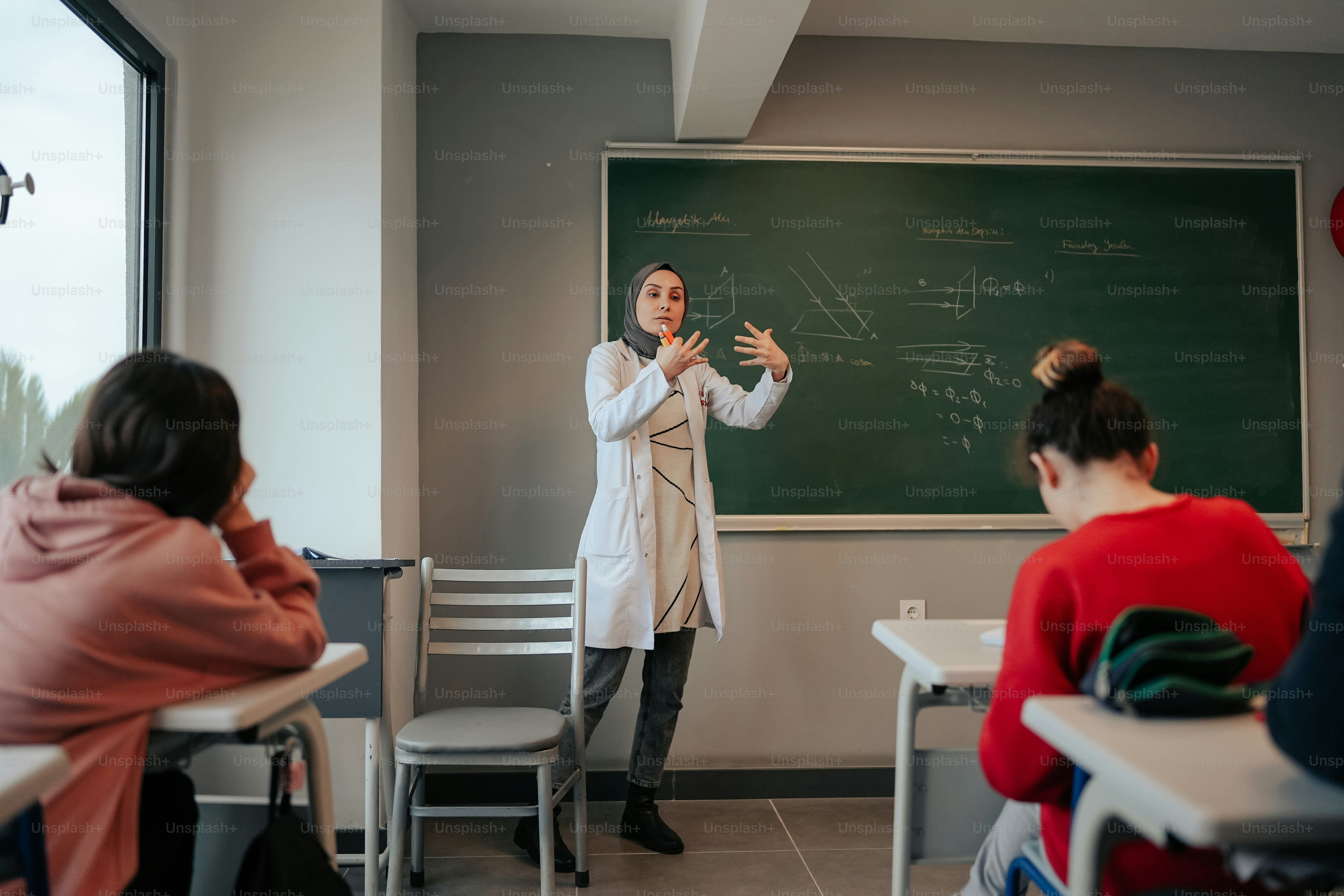 a woman standing in front of a blackboard in a classroom