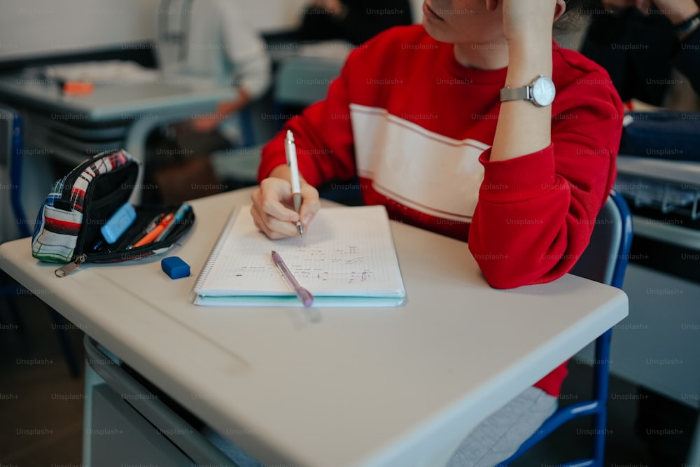 Una persona sentada en un escritorio escribiendo en un cuaderno