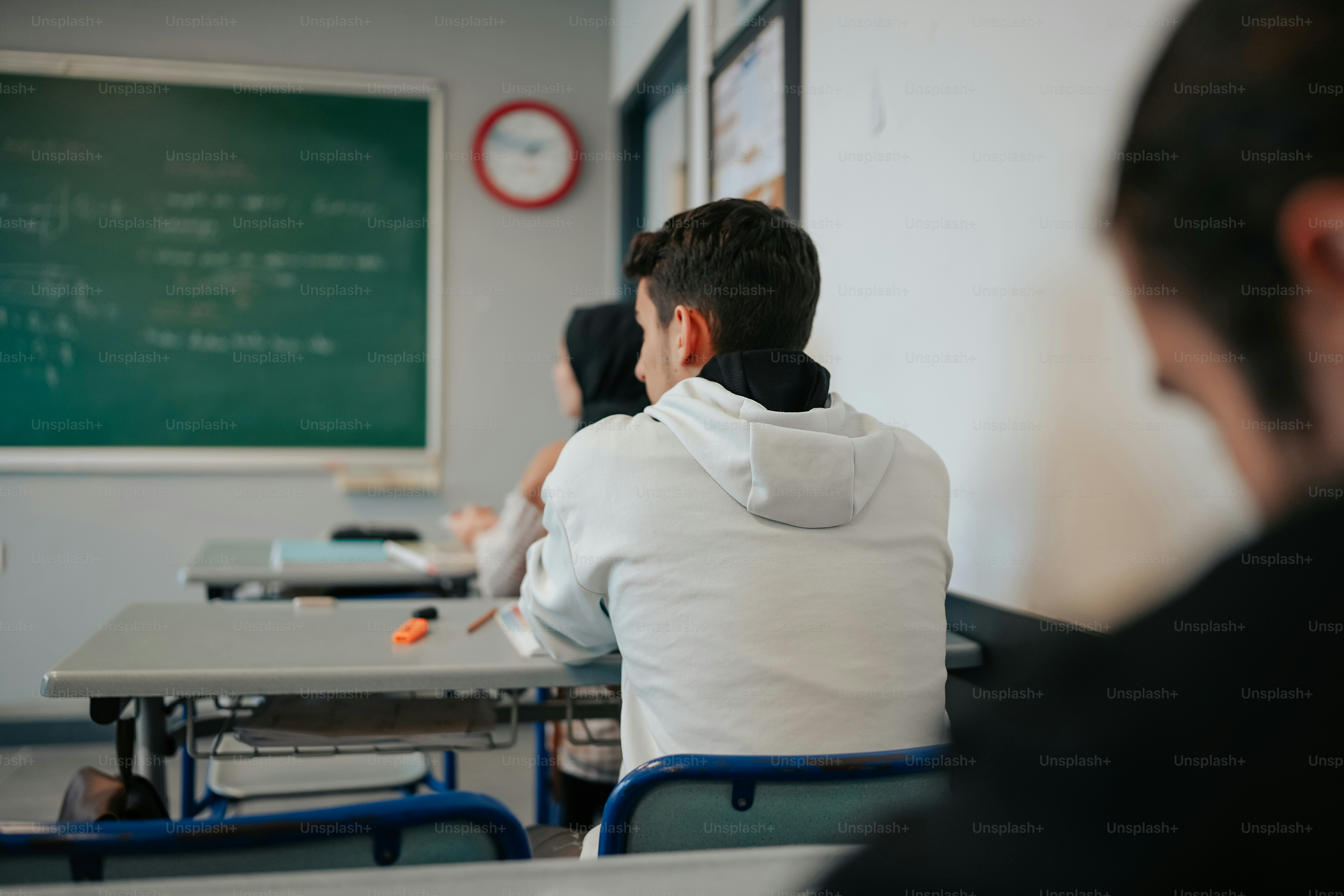a man sitting at a desk in front of a blackboard