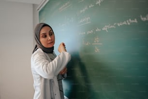 교실에서 칠판에 글을 쓰는 여자