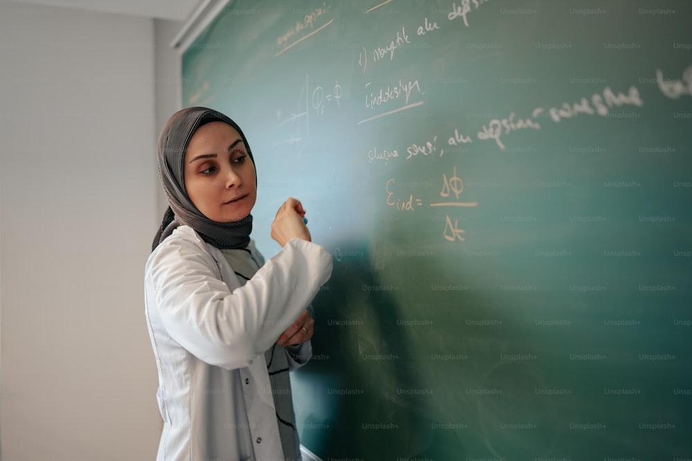 Eine Frau, die auf eine Tafel in einem Klassenzimmer schreibt
