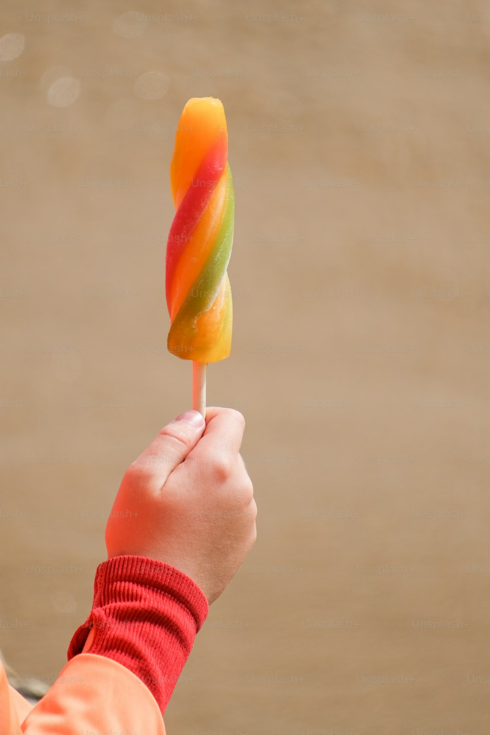 a person holding a colorful lollipop in their hand