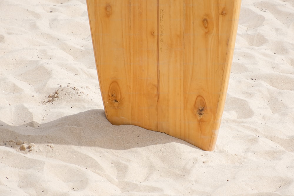 una tavola da surf che spunta dalla sabbia su una spiaggia