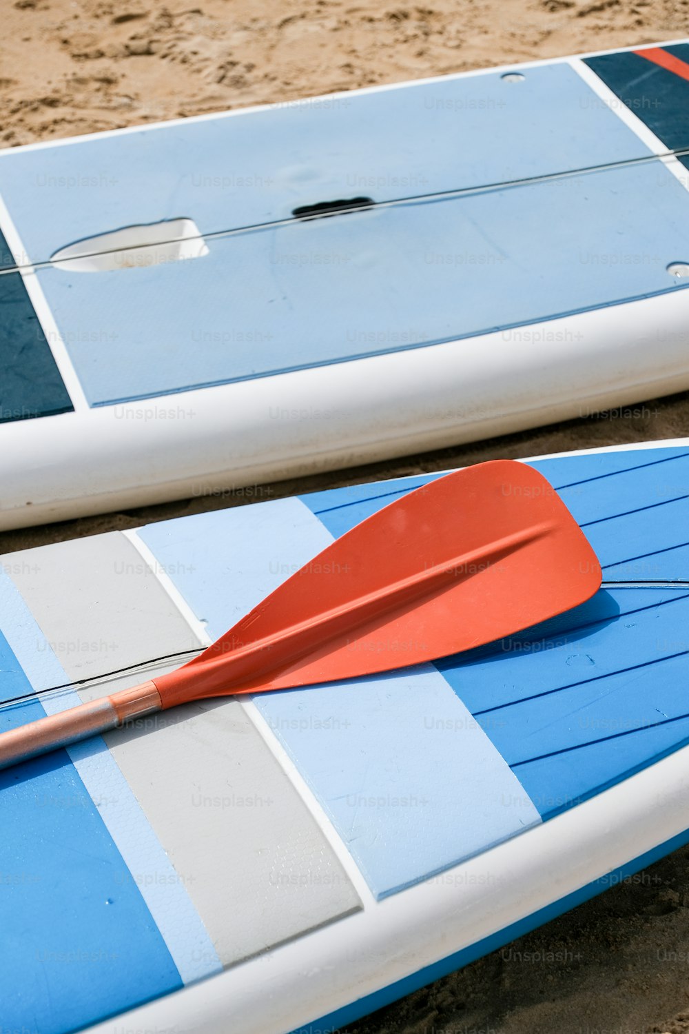 two surf boards with a red paddle on top of them