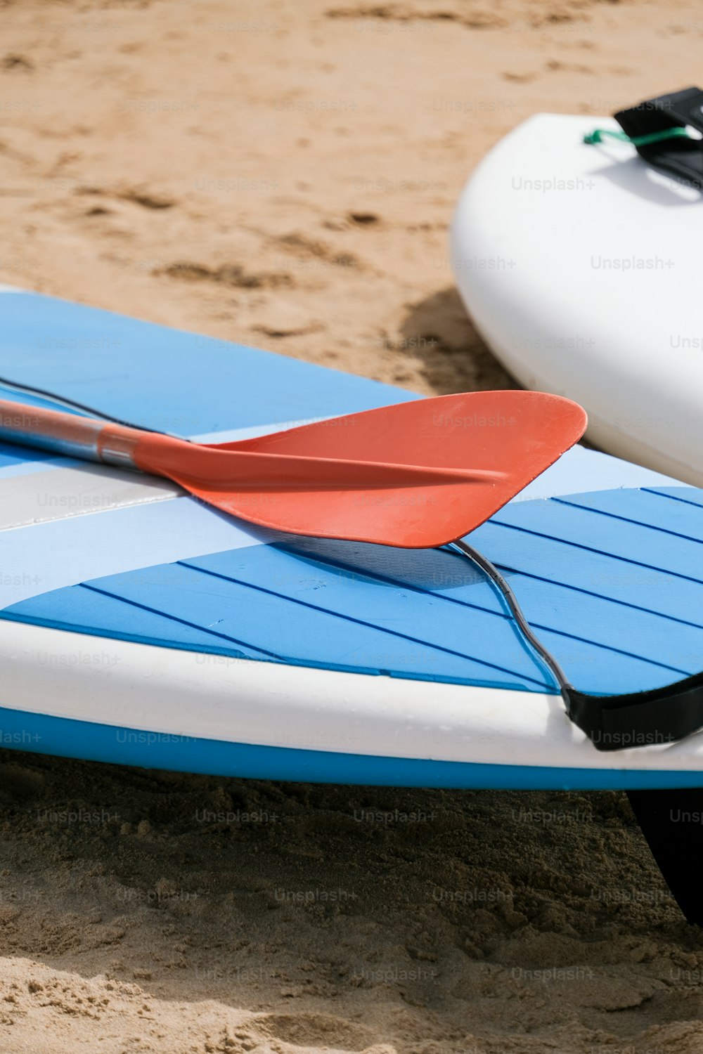 una pagaia rossa che giace sopra una tavola da surf blu e bianca