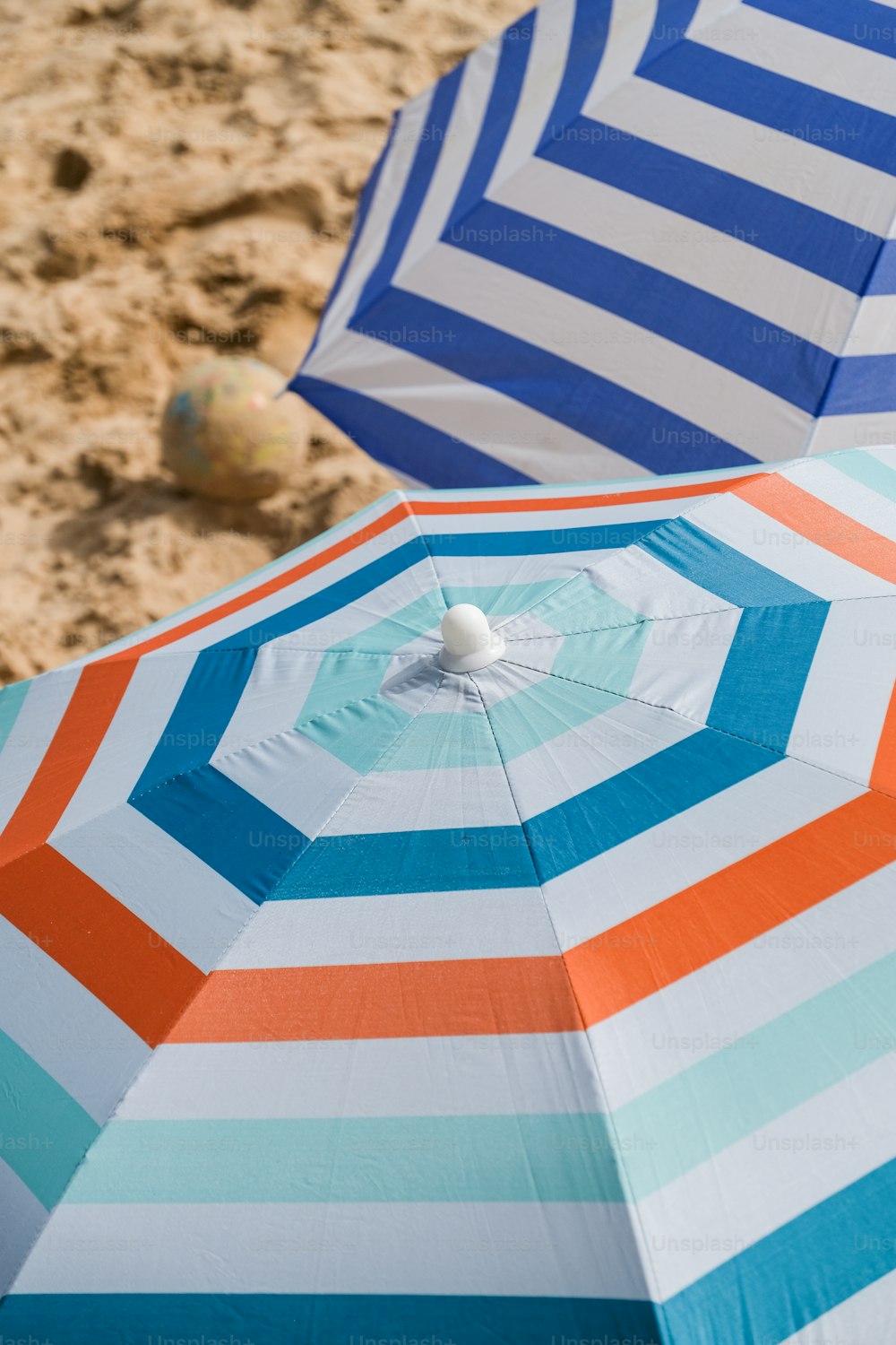 모래 사장 위에 앉아 있는 우산 두 개
