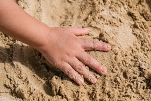 a child's hand on a pile of sand