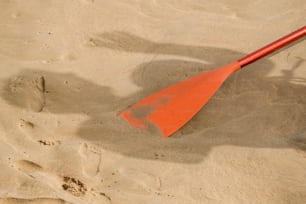une pagaie rouge assise au sommet d’une plage de sable