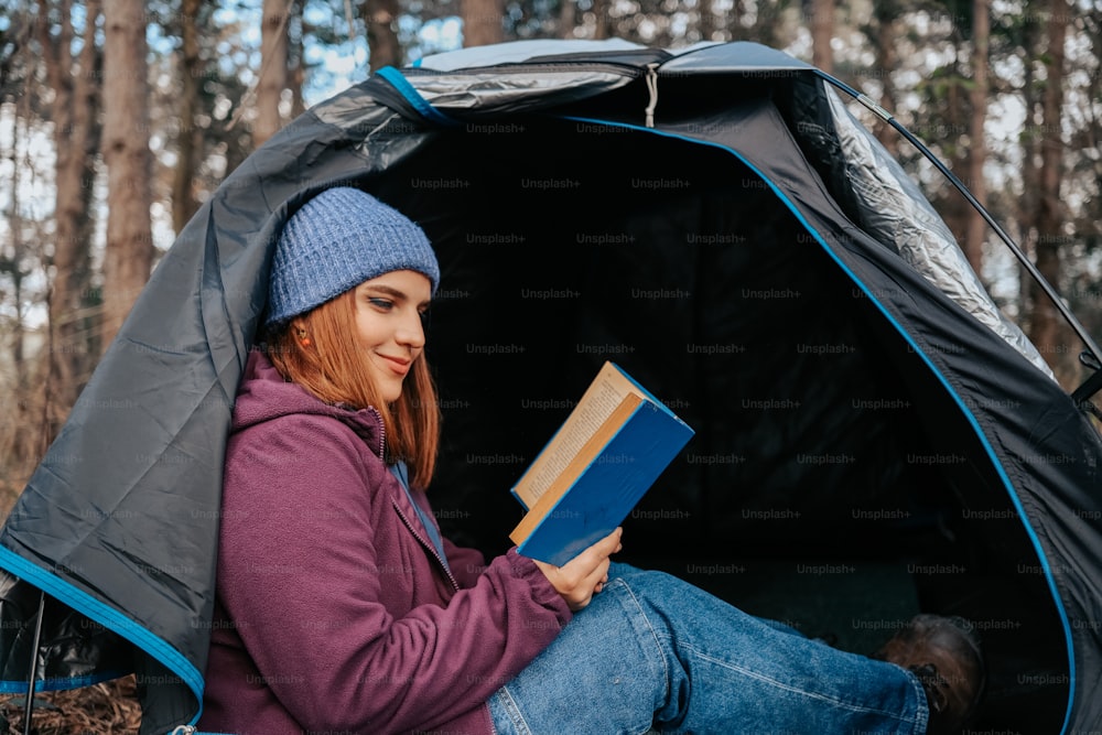 a woman sitting in a tent reading a book