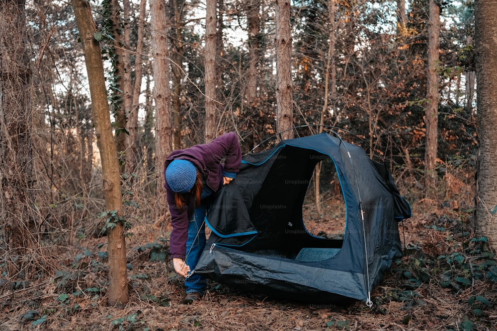 eine Person, die ein Zelt im Wald aufbaut