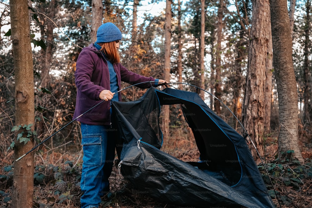 una persona in piedi nel bosco con una tenda