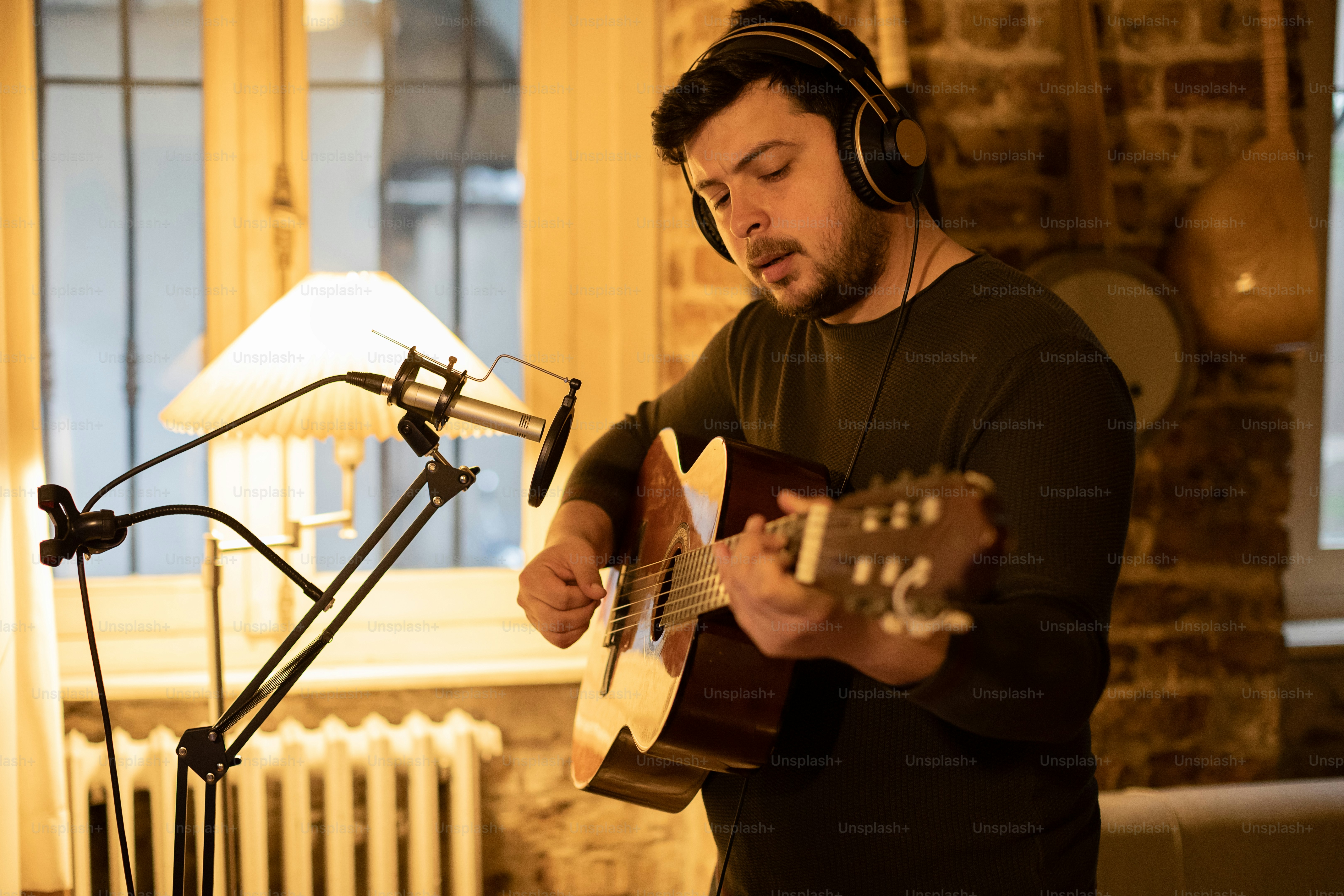 a man playing a guitar in front of a microphone