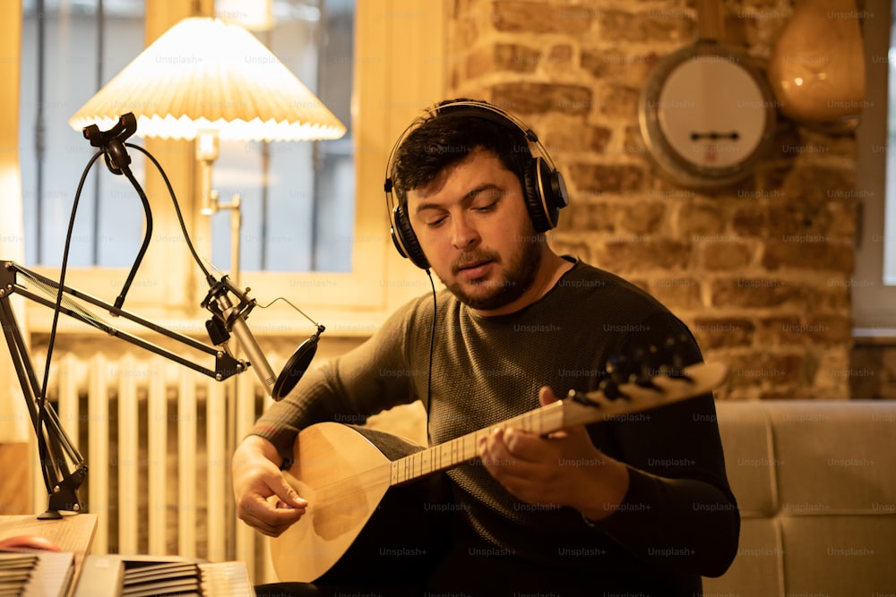 Un uomo seduto davanti a un microfono che suona una chitarra