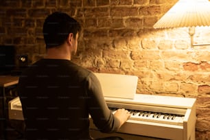 a man sitting at a piano in front of a lamp