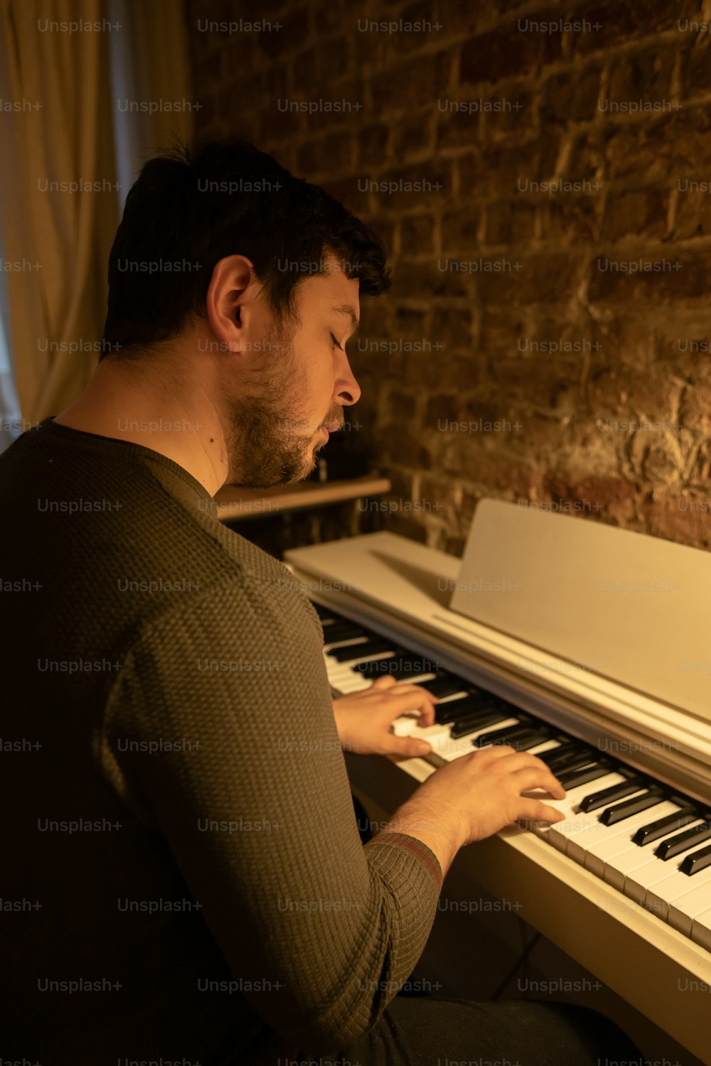 ピアノの前に座って楽器を演奏する男性