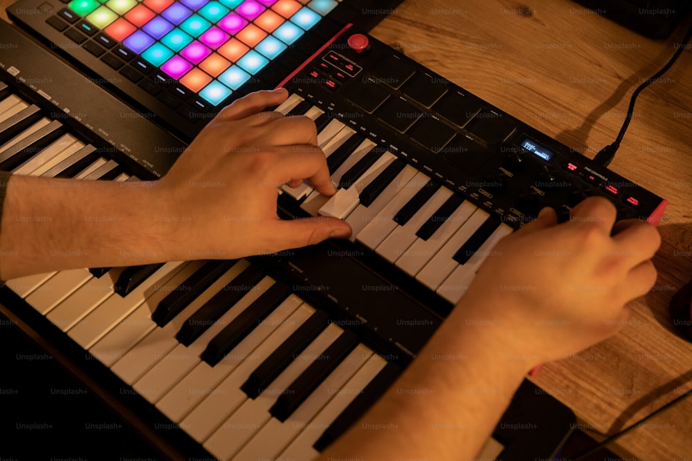 a person playing a keyboard with a colorful light on it