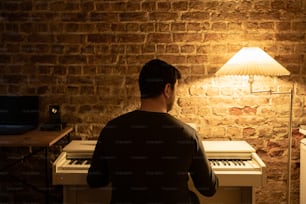 a man sitting at a piano in front of a brick wall