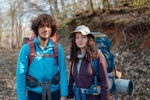 a man and a woman with backpacks standing in the woods