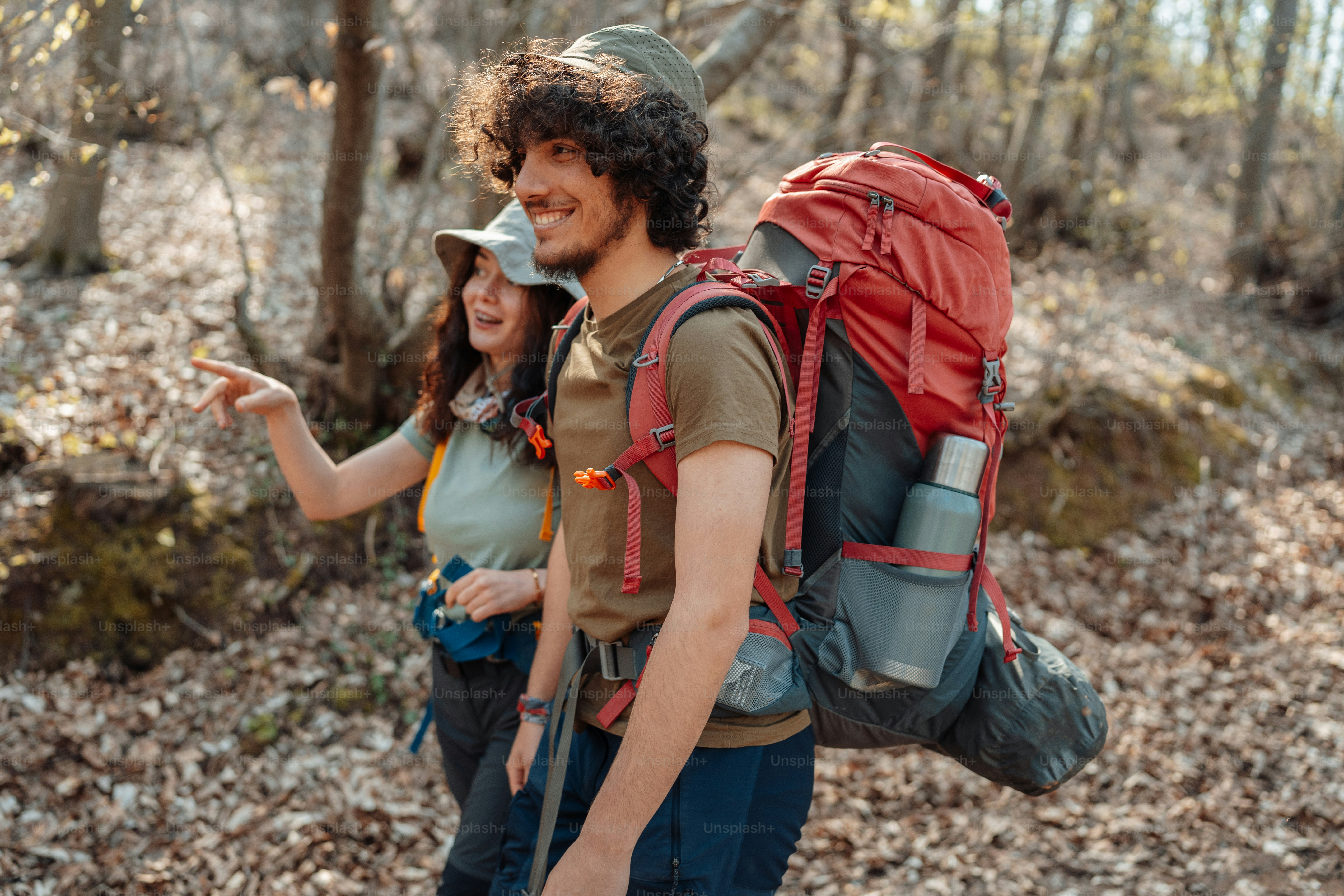 a man and a woman with backpacks walking through the woods