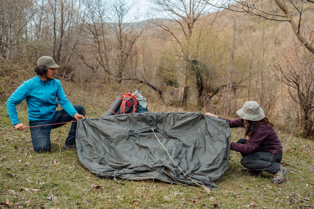 two women are setting up a tarp in the woods