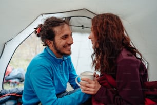a man and a woman sitting in a tent talking