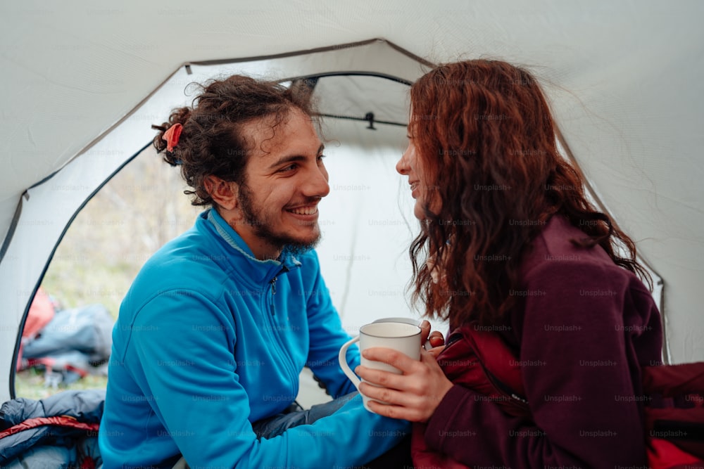 a man and a woman sitting in a tent talking