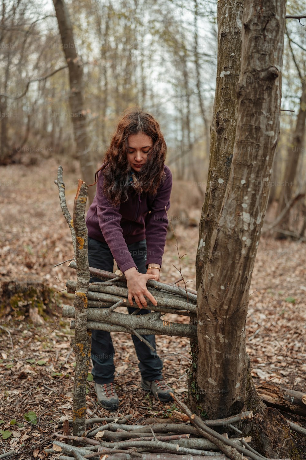 a woman leaning on a wooden fence in the woods