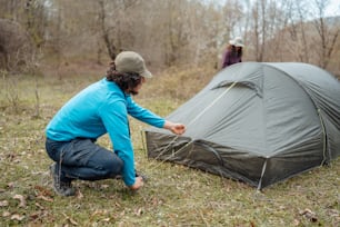 a man kneeling down next to a tent