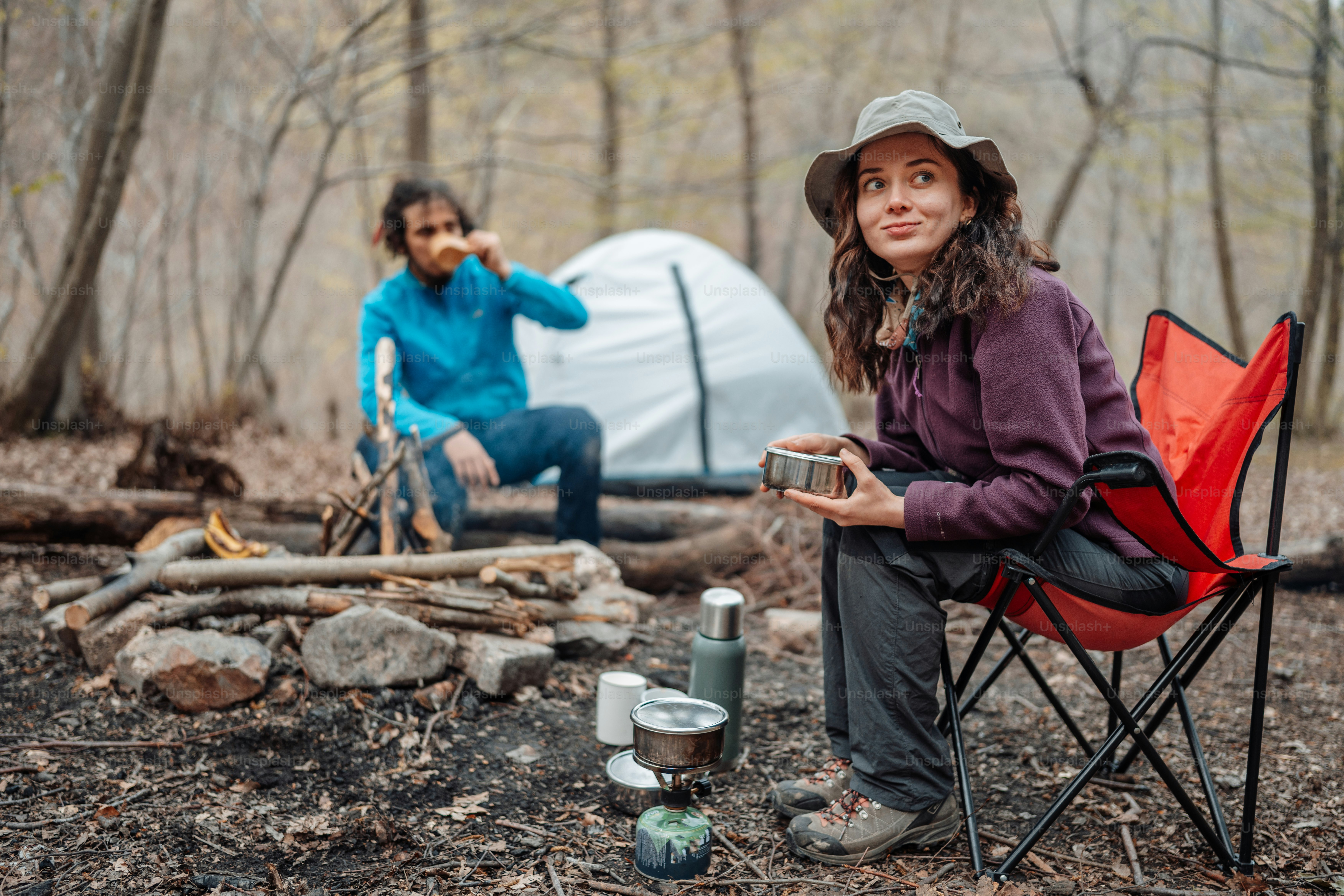 a woman sitting in a chair next to a campfire