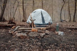 Ein Zelt im Wald in der Nähe eines Holzhaufens