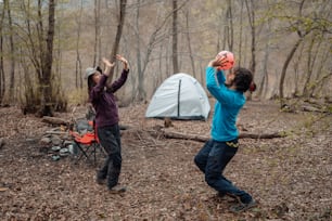 a couple of men standing next to a tent in the woods