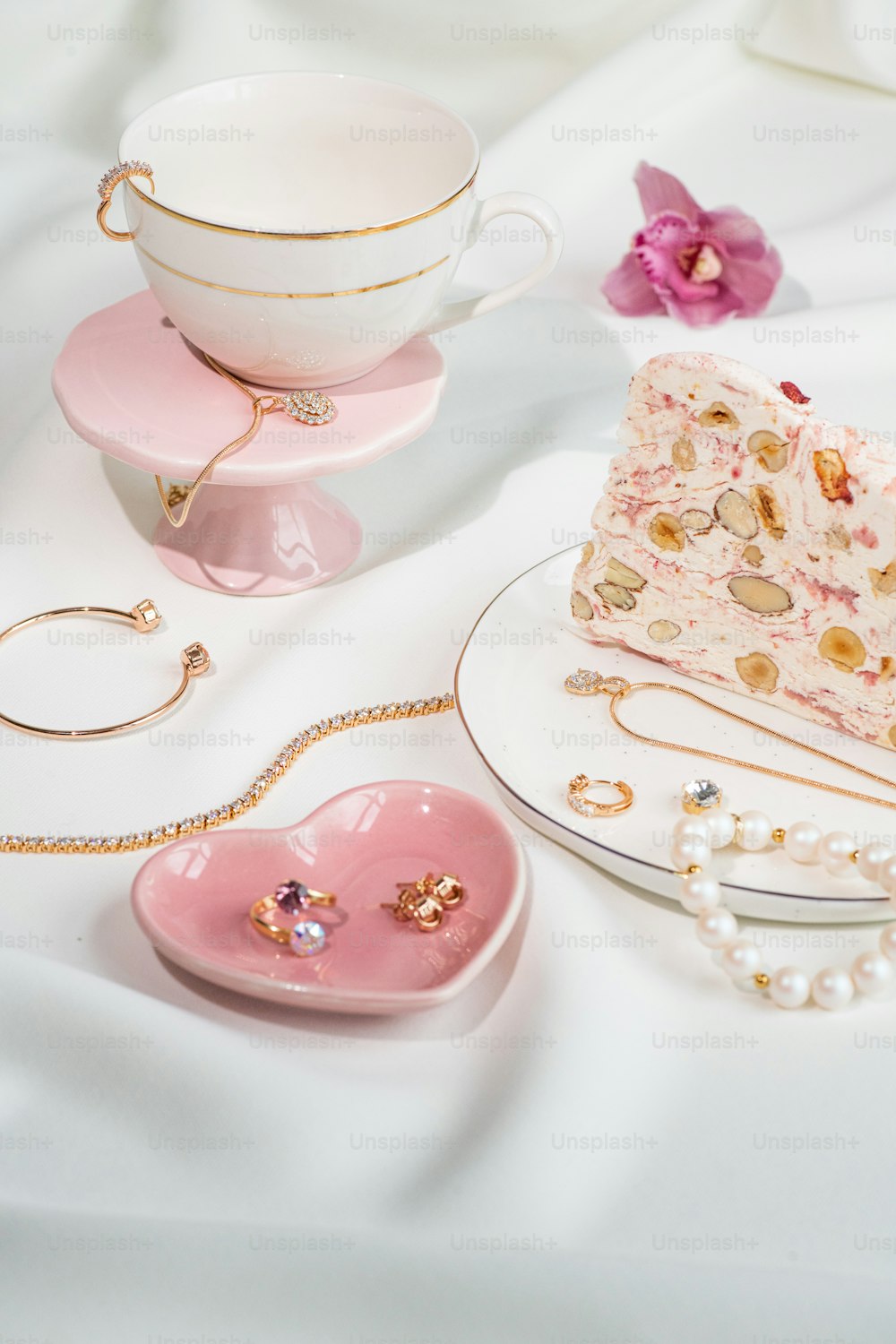 컵과 접시 옆에 분홍색 케이크를 얹은 테이블