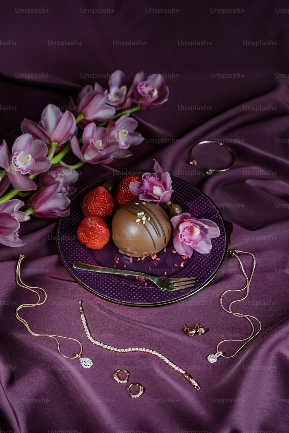 un piatto di cioccolatini e fiori su un panno viola