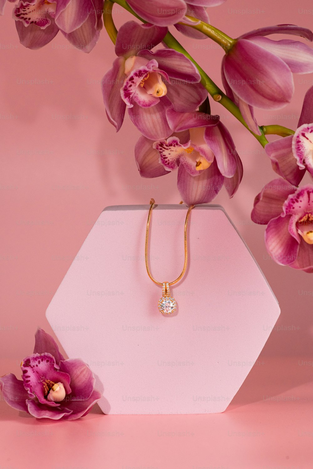 a pink vase with flowers and a diamond necklace