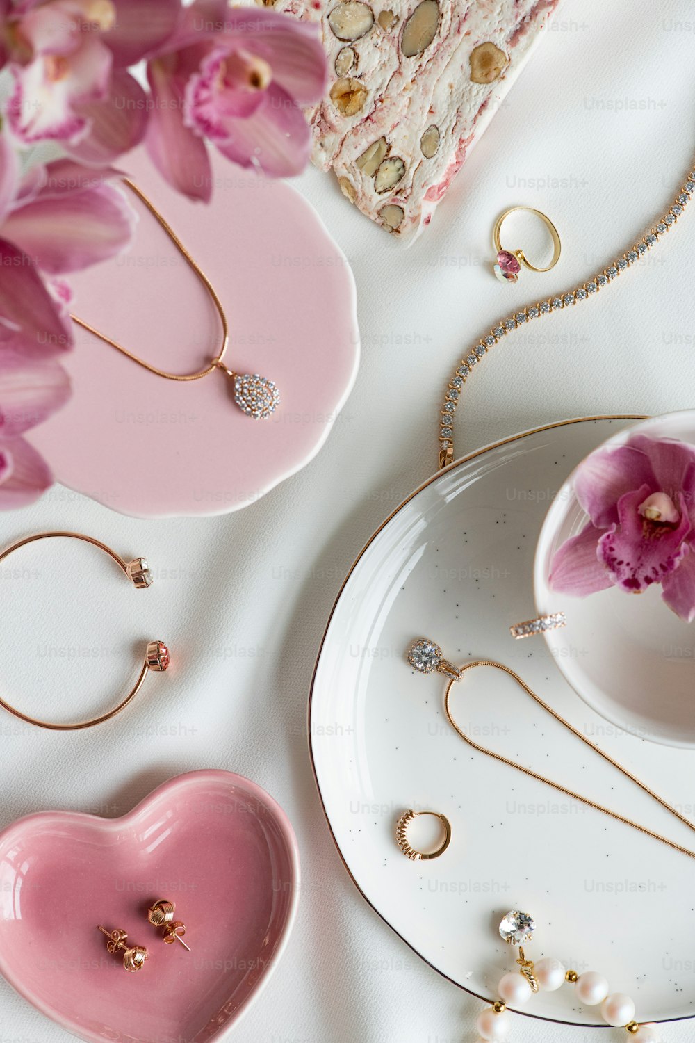 uma mesa coberta com flores cor-de-rosa e joias