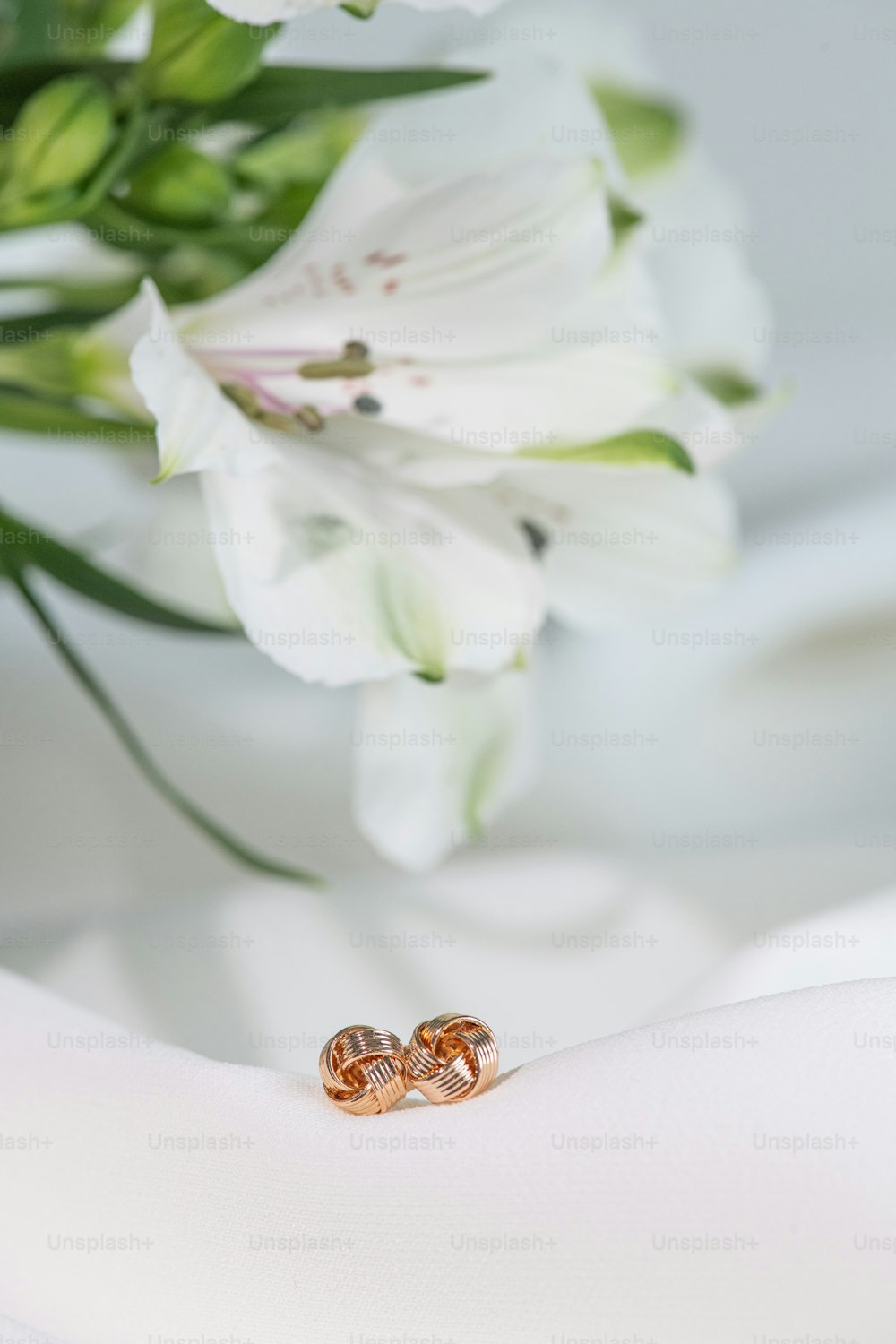 two gold wedding rings sitting on a white cloth
