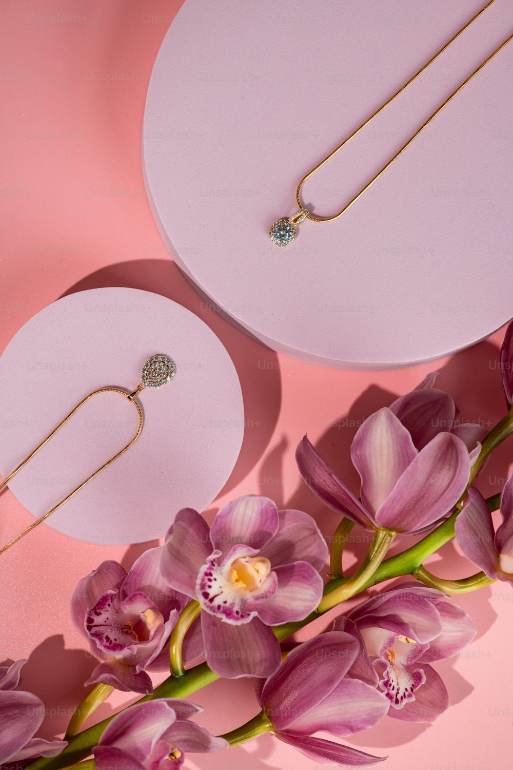 a pair of necklaces sitting on top of a pink surface