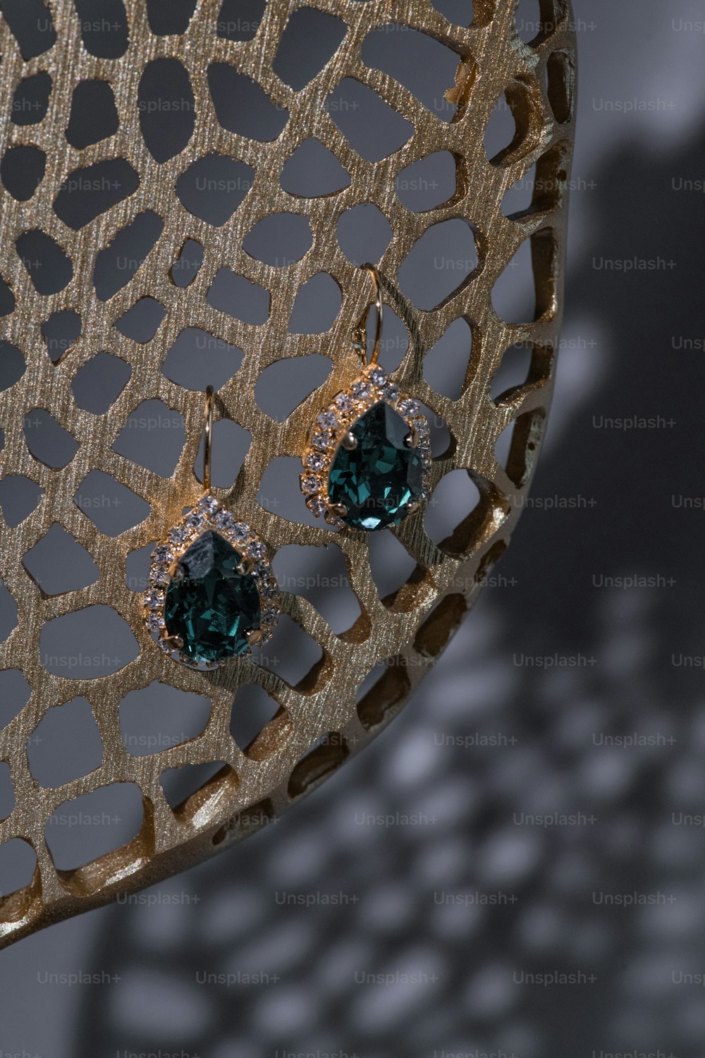 a pair of green stone earrings on a metal stand