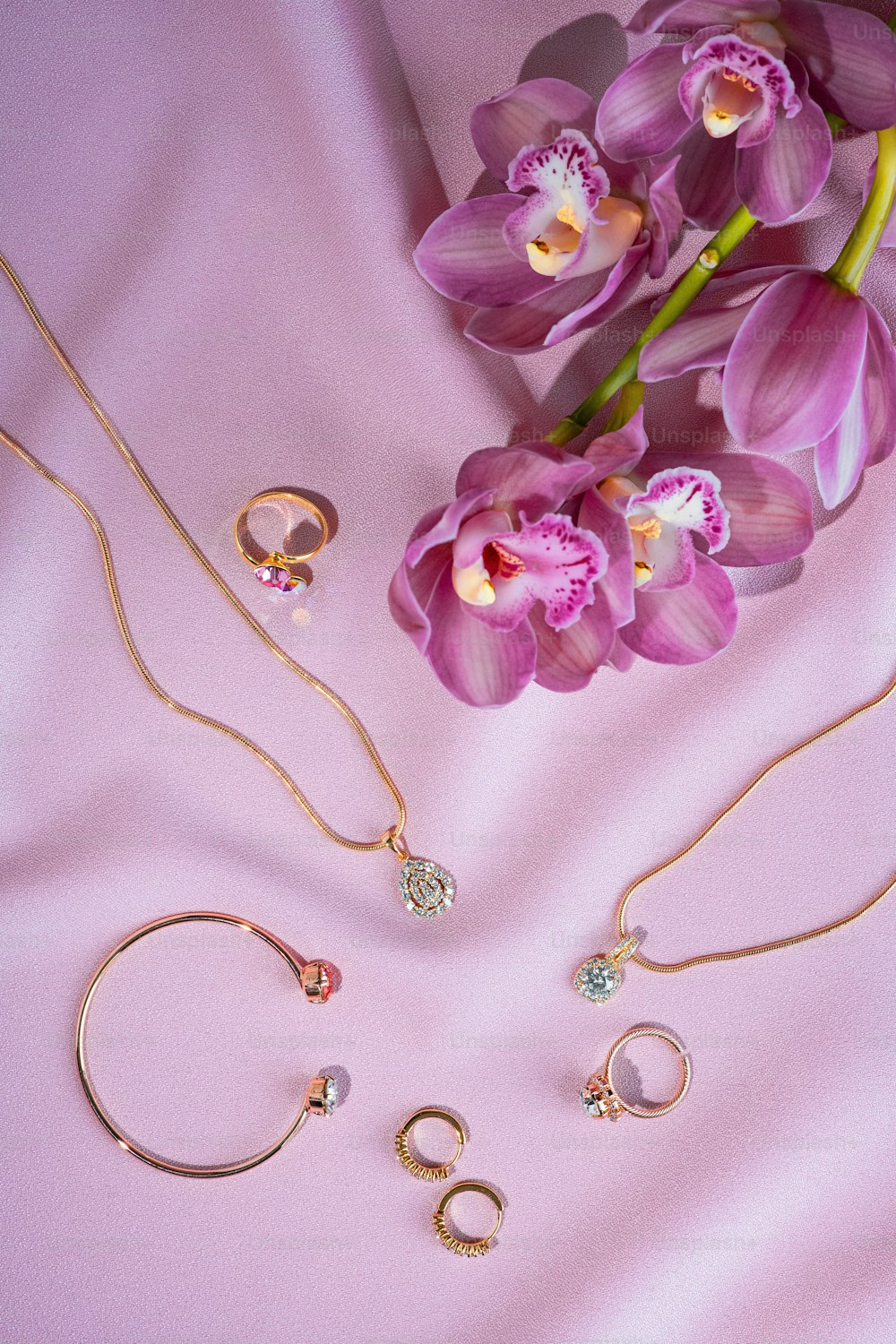 a bunch of jewelry laying on a pink surface